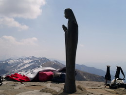 La Madonnina posta sul piedistallo dove si trova la grande croce in vetta al Marmagna. Sullo sfondo la dorsale dell'Appennino Tosco Emiliano